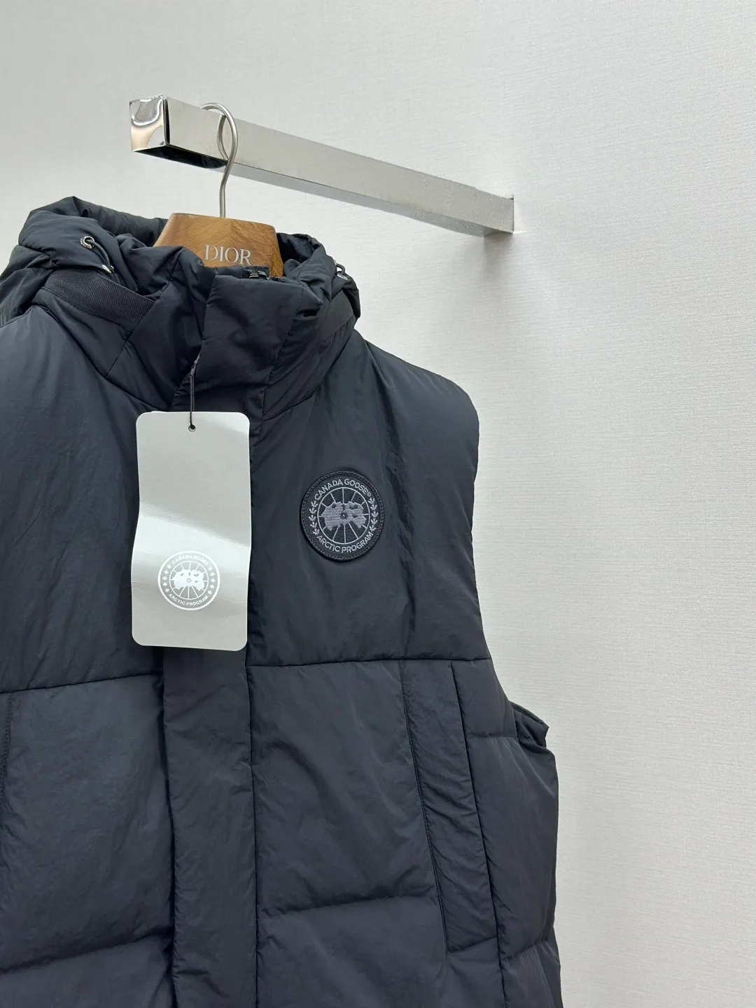P760 Canada Goose logo hooded down vest Fabric selection: The use of high-quality protective nylon fabric not only enhances the wear resistance of the surface, but also takes into account wind resistance, ensuring excellent performance in various harsh weather conditions.  90 national standard high-quality white duck down: selected high-loft down, weighing 170g, light and warm, with excellent temperature locking performance and good resilience.  Three-dimensional quilting process: Precision thread reinforcement to prevent velvet drilling and ensure that the fluffy and resilient elasticity lasts as new.  Details: Use polyester as the base for woven webbing, and use high-precision computer embroidery to decorate the brand letters on the webbing. The edges of the pattern are clear, the stitches are fine and even, and multiple layers of embroidery threads are stacked to enhance the three-dimensional effect. Accessories: Customized logo Customized zipper pendant Customized hem elastic buckle Customized snap button SIZE: S M L XL